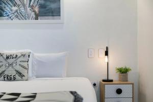 a white bedroom with a bed and a lamp at Noosa Blue Resort in Noosa Heads