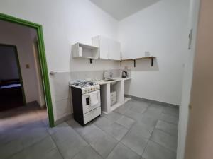 une petite cuisine avec une cuisinière et des armoires blanches dans l'établissement Juanes, à Salta
