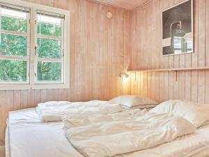 a large white bed in a room with wooden walls at Holiday home Aakirkeby LXIII in Vester Sømarken