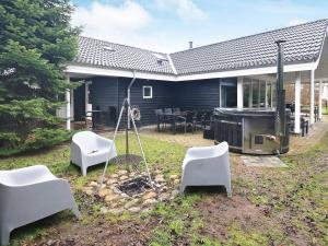 a backyard with white chairs and a grill and a house at Holiday home Væggerløse LXXXIX in Marielyst