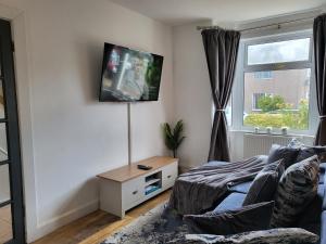 Coventry Cosy Home - Great location for Contractors, Families, Relocators, close Walsgrave Hospital and Motorways في Wyken: غرفة معيشة مع أريكة وتلفزيون على الحائط