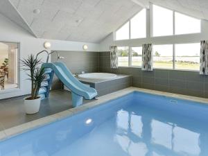 łazienka z błękitnym basenem ze zjeżdżalnią w obiekcie 18 person holiday home in Bogense w mieście Bogense