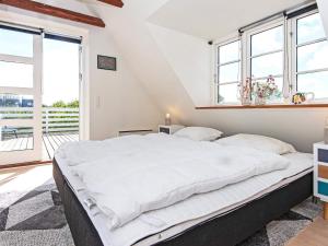 a bedroom with a large white bed with windows at Holiday home Ebeltoft CCXXII in Ebeltoft