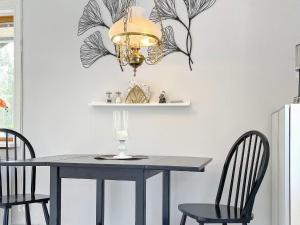 a dining room table with two chairs and a chandelier at Holiday home Rejmyre II in Rejmyre