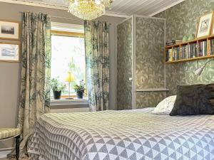 a bedroom with a bed and a window and a chandelier at Holiday home Rejmyre II in Rejmyre