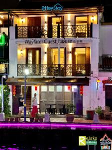 two people walking in front of a guest house at night at Wayfarer Guest House Jonker Street Melaka By Heystay Management in Melaka