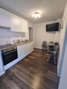 a kitchen with white cabinets and a table with chairs at Apartman Migliore in Sesvete