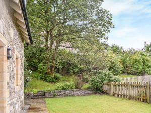 a brick house with a fence and a yard at Frasers Cottage in Salen