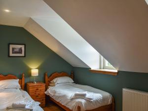 a bedroom with two beds and a window at Frasers Cottage in Salen