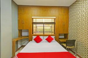 1 dormitorio con 1 cama con 2 almohadas rojas en OYO Flagship Karipur Residency, en Kondotti