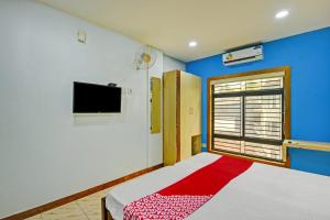 a bedroom with a bed and a tv on the wall at OYO Flagship Karipur Residency in Kondotti