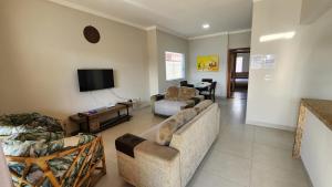 uma sala de estar com um sofá e uma televisão em Casa Peruibe com Piscina Mtk2 em Peruíbe