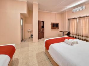 um quarto de hotel com duas camas e uma casa de banho em RedDoorz Syariah near Pasar Raya Padang em Padang