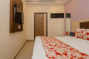 a bedroom with a bed and a tv on the wall at Hotel Golden Nest Near Chhatrapati Shivaji International Airport in Mumbai