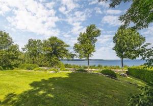 a large grassy yard with a view of the water at Amazing view of 4 bedrooms, 3 bathrooms 4-season cottage in Wiarton