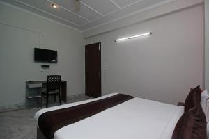 um quarto com uma cama, uma secretária e uma televisão em OYO Flagship 9075 Petals Inn em Noida