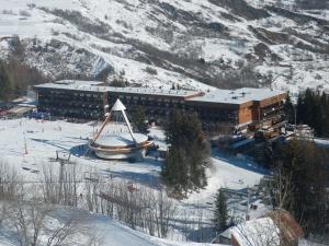 un grande edificio nella neve di fronte a una montagna di Duplex spacieux au pied des pistes avec accès piscine - FR-1-267-255 a Villarembert