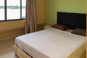 Un dormitorio con una gran cama blanca y una ventana en Hotel Laut Jaya Tanjung Pinang RedPartner en Tanjung Pinang