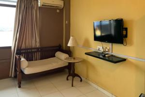 a room with a tv and a chair and a table at Hotel Laut Jaya Tanjung Pinang RedPartner in Tanjung Pinang 