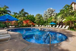 a large swimming pool with chairs and umbrellas at Waikomo Streams 203 in Koloa