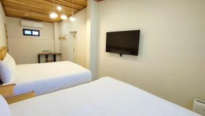 1 dormitorio con 2 camas y TV de pantalla plana en Island Flower Inn en Nangan