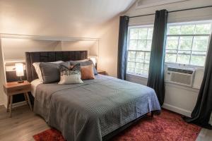 a bedroom with a bed and two windows at J Birds' Cottage Midtown Memphis in Memphis