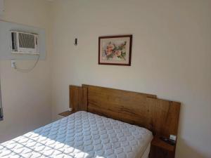een slaapkamer met een bed en een foto aan de muur bij Apartamento Edifício Arpoador (Praias Asturias-Tombo) in Guarujá