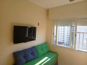 - un canapé vert dans une pièce avec fenêtre dans l'établissement Apartamento Edifício Arpoador (Praias Asturias-Tombo), à Guarujá