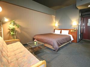 a hotel room with a bed and a couch at HOTEL LiVEMAX BUDGET Yokohama Tsurumi in Yokohama