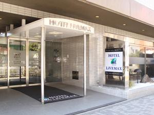 a hotel entrance with a sign in the window at HOTEL LiVEMAX BUDGET Yokohama Tsurumi in Yokohama