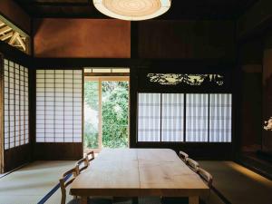 a dining room with a wooden table and windows at RITA Izumifumoto in Izumi