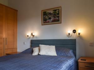 a bedroom with a blue bed with two lights on the wall at Harvest View in Coton