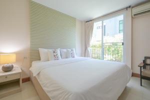 a bedroom with a large white bed and a window at Shamrock Hotel Pattaya in Nong Prue