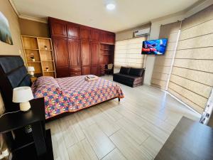 1 dormitorio con 1 cama, 1 silla y TV de pantalla plana en Master Suite Next To San Marino Shopping, Balcony, en Guayaquil