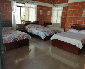 1 dormitorio con 2 camas y pared de ladrillo en CASA CAMPESTRE EL RINCON VERDE, en Rivera