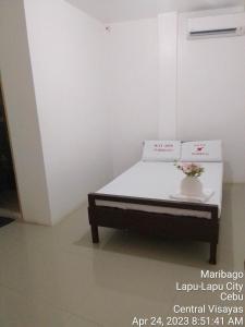 WJV INN MARIBAG0 في Maribago: غرفة نوم مع سرير مع إناء من الزهور عليه