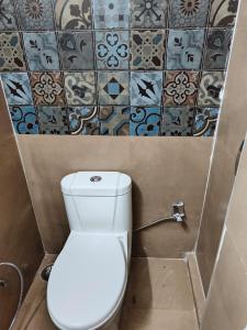 a white toilet in a bathroom with tiles on the wall at Fursat, exclusive solitude! in Rāmgarh