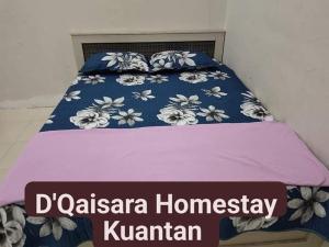 een bed met een blauwe en witte deken en een bord bij D'Qaisara Homestay Kuantan in Kampong Bugis
