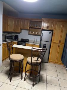 een keuken met houten kasten, een koelkast en stoelen bij Departamento Irene in San Felipe