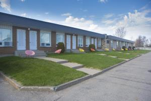 a building with a row of chairs in the grass at Motel Vaudreuil in Vaudreuil-Dorion