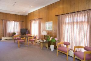 a waiting room with chairs and a table and a tv at Motel Vaudreuil in Vaudreuil-Dorion