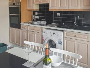 a kitchen with a washing machine and a bottle of wine at Harbour View House in Anstruther