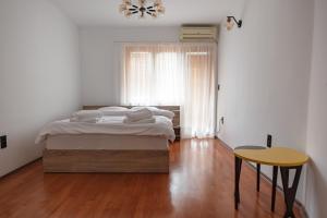 a bedroom with a bed and a table and a window at Lux House with own parking in Skopje in Skopje