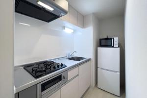 a white kitchen with a stove and a refrigerator at toggle BUNKYO KORAKUEN in Tokyo
