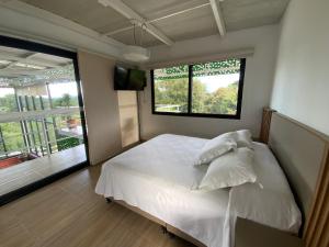 1 dormitorio con cama blanca y ventana grande en Finca Hotel 12 Palmas- Aeropuerto JMC, en Rionegro