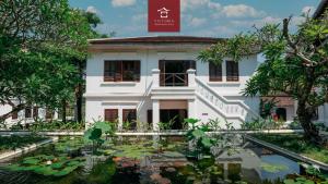 a house with a pond in front of it at Victoria XiengThong Palace in Luang Prabang