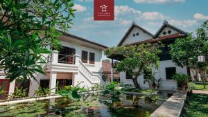 a house with a pond in front of it at Victoria XiengThong Palace in Luang Prabang