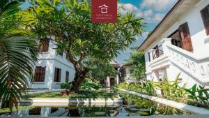 a courtyard of a building with a tree and a pond at Victoria XiengThong Palace in Luang Prabang