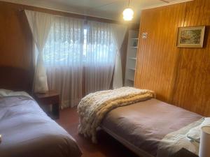 een slaapkamer met 2 bedden en een raam bij HOSTAL AONKEN in Coihaique