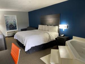 Habitación de hotel con cama y bañera en Clairmont Inn & Suites - Warren, en Warren